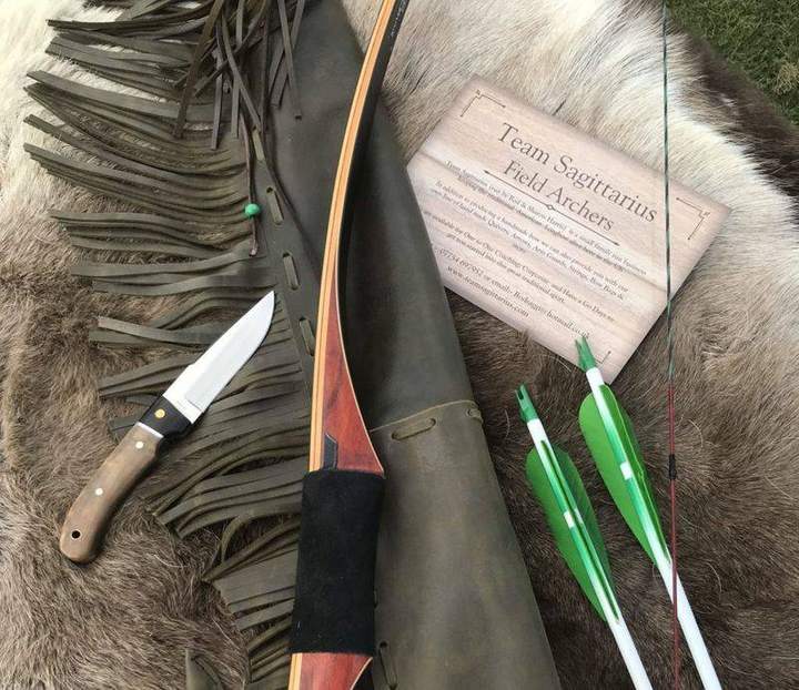 Traditional longbow with a leather quiver and arrows on a field archery setup