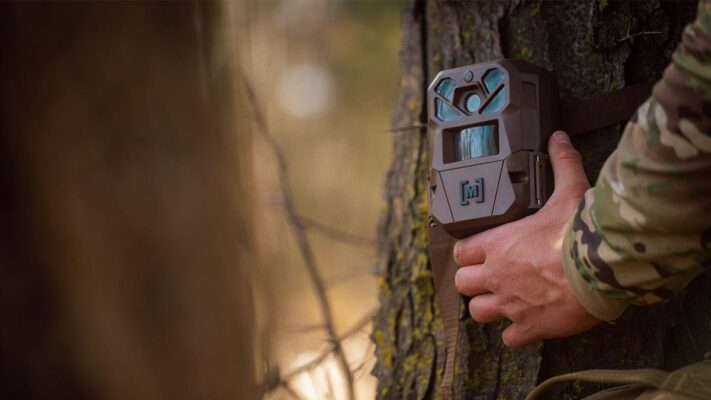 Trail camera placement: bowhunter mounting cam on tree