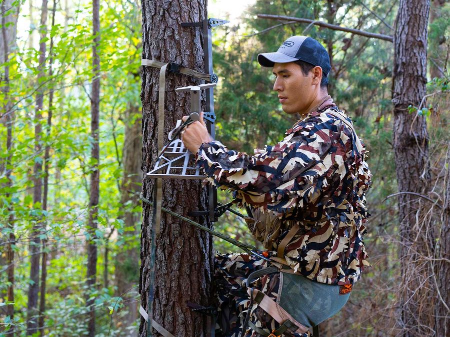 Bowhunter setting up treestand for deer grunt call hunting