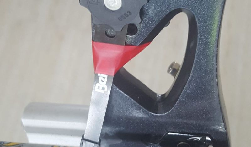 Archery clicker mounted on a recurve riser with the arrow underneath