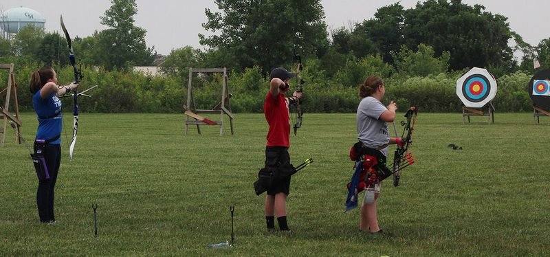 Recurve and compound archers on the shooting line taking aim at targets