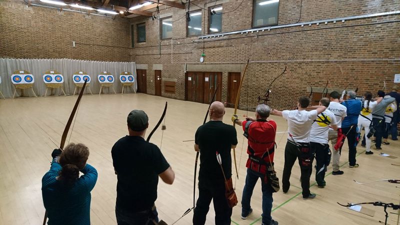 Line of archers practicing on multiple target faces to tighten their arrow groups