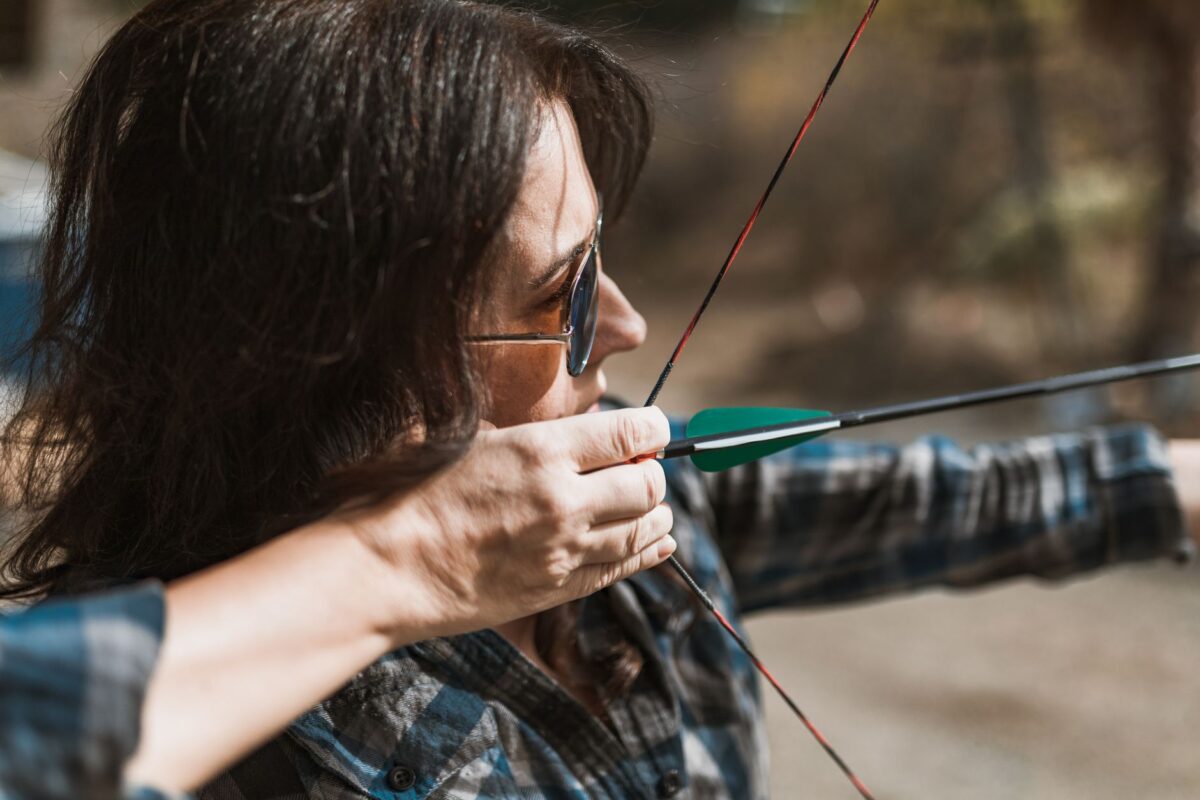 Female archer drawing recurve bow outdoors