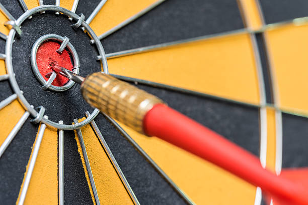 closeup red dart arrow hitting in target bullseye of dartboard closeup red dart arrow hitting in target bullseye of dartboard