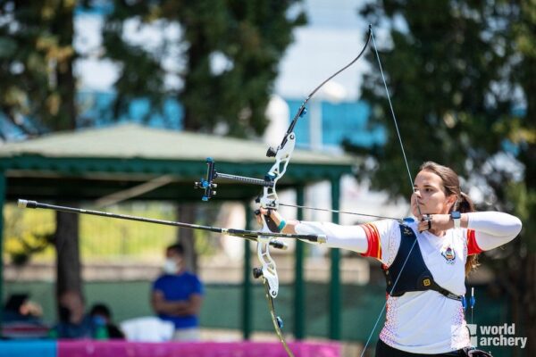 Beginner archery: female archer at full draw with a recurve bow aiming outdoors