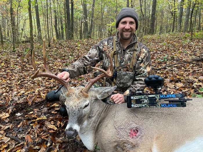Bowhunter posing with harvested whitetail deer after ethical shot placement with compound bow