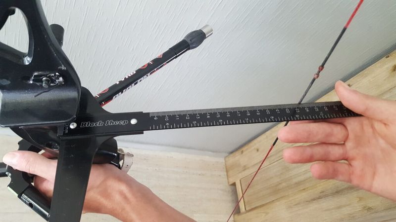 Checking brace height on a recurve bow with a T-square gauge