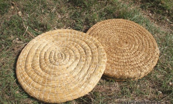 Two coiled straw archery targets resting on grass at an outdoor range