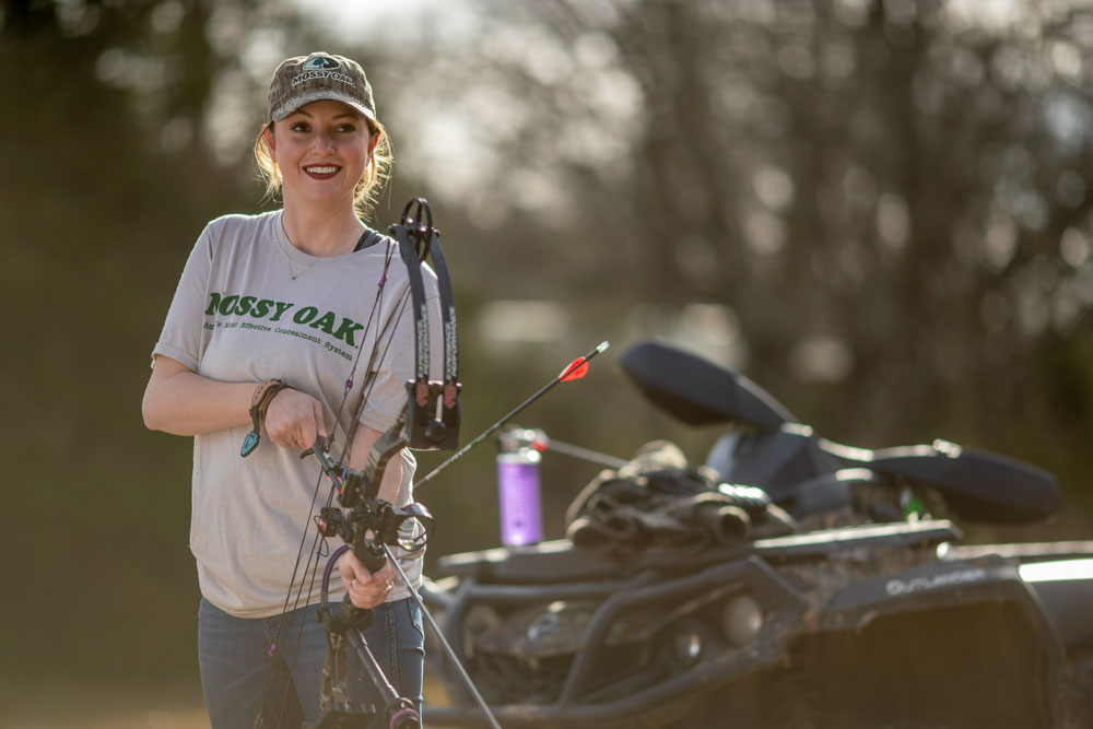 Woman archer with compound bow practicing for 3D archery course