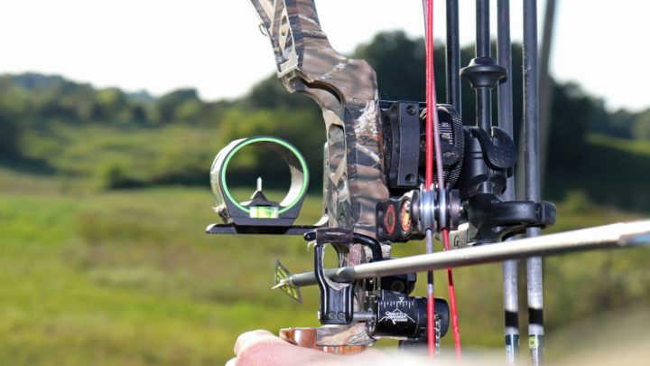 compound bow with arrow rest sight and stabilizer in outdoor field setting for bowhunting