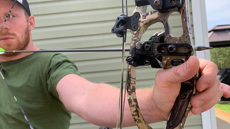 Archer at full draw showing compound bow grip and brace height
