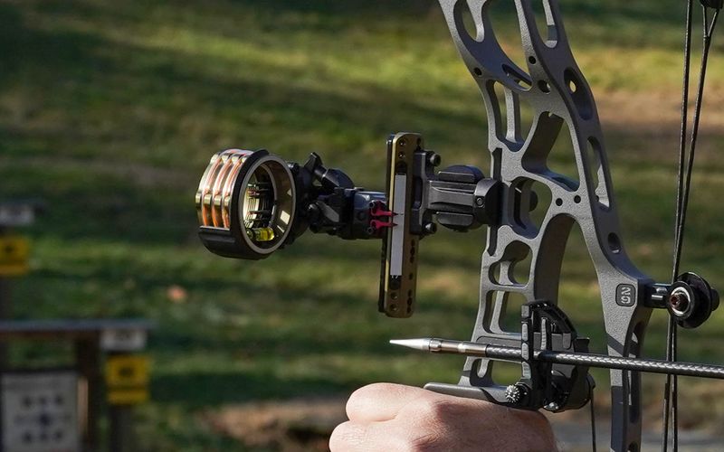 Compound bow drawn with the sight and nocked arrow lined up on target before the release fires