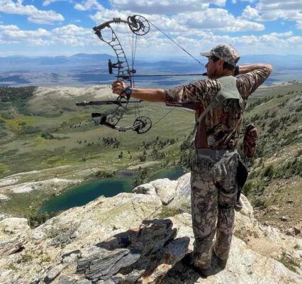 Bowhunter at full draw with compound bow on mountain ridge during hunting season
