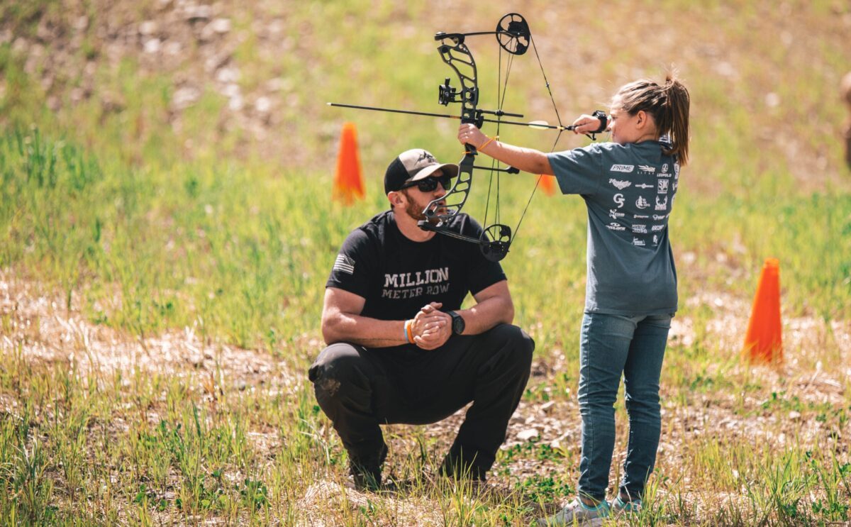 Coach checking an archer's form to fix arrow flight problems