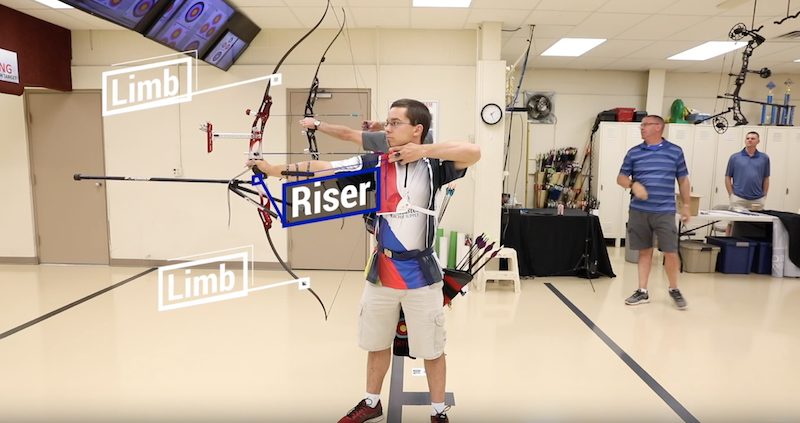Archer at full draw with a strung Olympic recurve bow