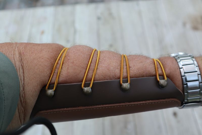 Close-up of leather archery arm guard worn on forearm with elastic cord straps