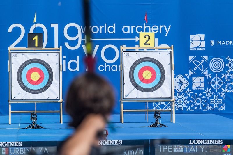 Two outdoor archery target faces on wooden stands at a range