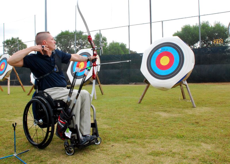 Para archery competitor shooting from a wheelchair at outdoor targets