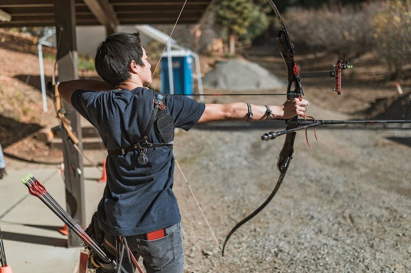 Recurve archer at outdoor archery range with proper form and arm guard