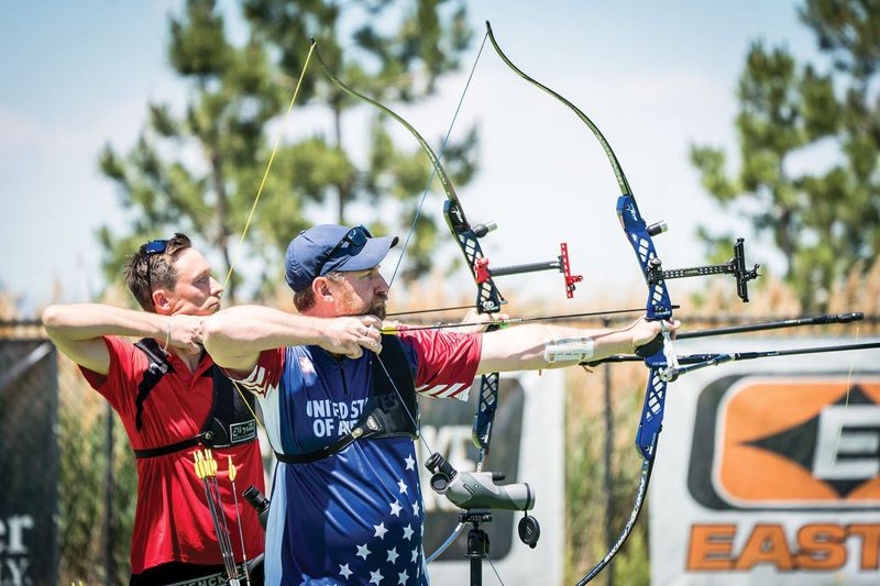 Two recurve archers at full draw holding a consistent anchor point to group arrows tighter