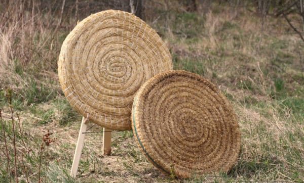 Traditional coiled straw archery target on a wooden stand at a range