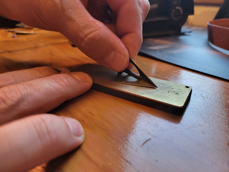Three-blade broadhead being sharpened on a diamond stone by hand