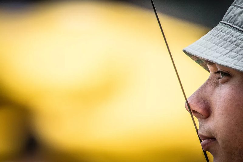 Archer sighting bow with controlled breathing and intense focus at competition