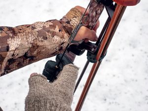 traditional bowhunter in camo using archery shooting glove on drawing hand