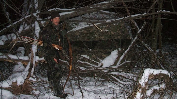 Bowhunter approaching ground blind through snow during late season hunt