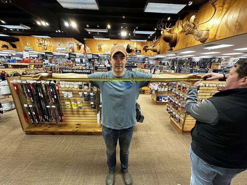 Archery shop measuring wingspan with tape for compound bow draw length calculation