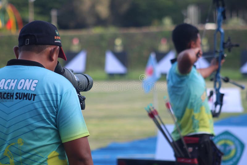 Banda Aceh, Indonesia - September 19, 2025: A male archer, in a full draw position, holds a modern compound bow on an outdoor