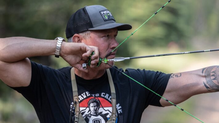 Archer at full draw properly aligned through compound bow peep sight