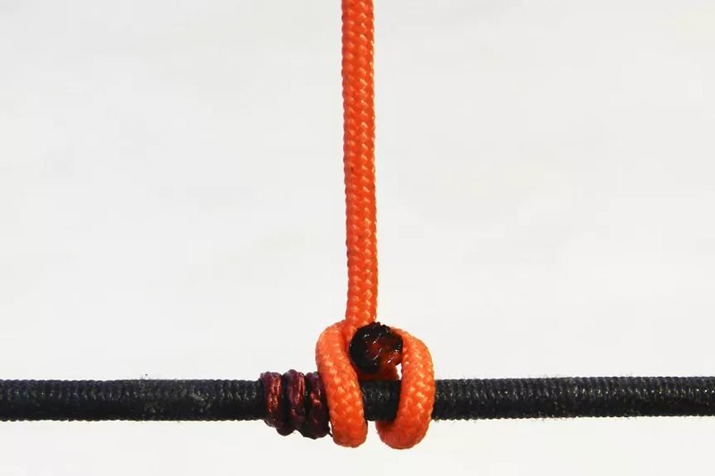 Tightening the D-loop knot against the bowstring with nocking pliers
