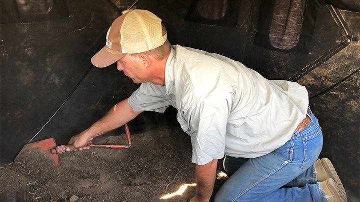 Hunter staking down ground blind with guy lines for wind stability