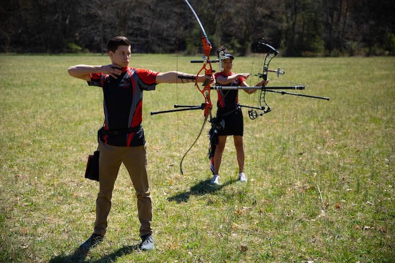 Traditional recurve archers shooting outdoors comparing different arrow types and setups